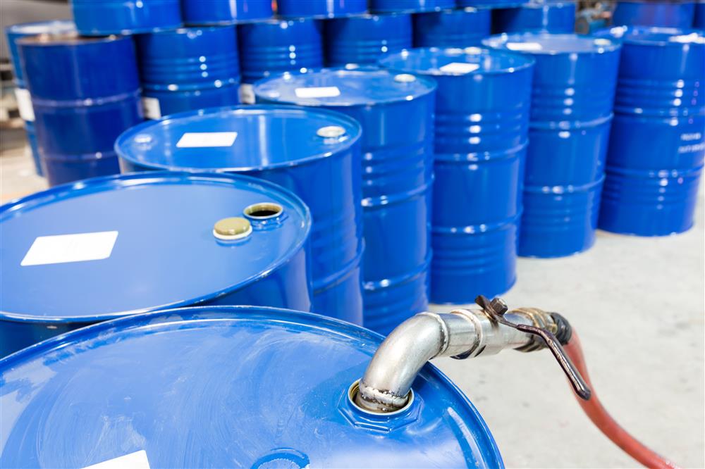 Metal drums with steel fittings being filled with oil.