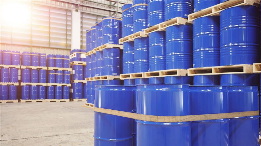 A collection of new steel drums in a warehouse with reconditioned poly drums.